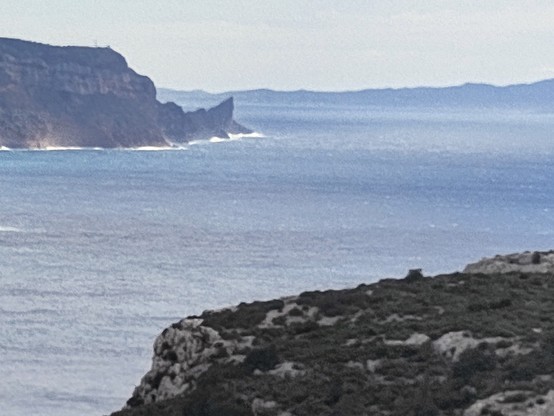 Man sieht die Küste bei Marseille und die weite des Mittelmeeres. An der rechten Seite ragt ein Felsen nach oben, der wie eine Haifischflosse aussieht.