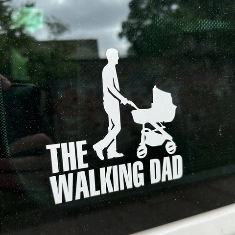 Foto eines Aufklebers auf einer Autoscheibe. Zu sehen ist als Silhouette ein Mann, der einen Kinderwagen schiebt. Darunter steht geschrieben: „The Walking Dad“.