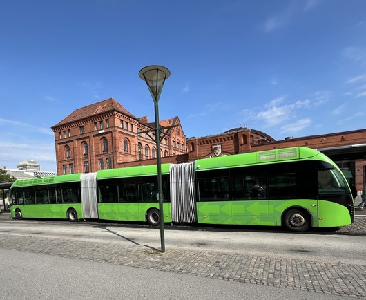 A three section super long green bus