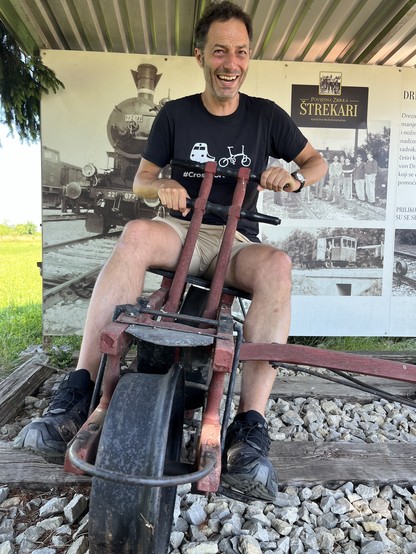 Jon riding a peculiar pedal draisine in a hut at a station 
