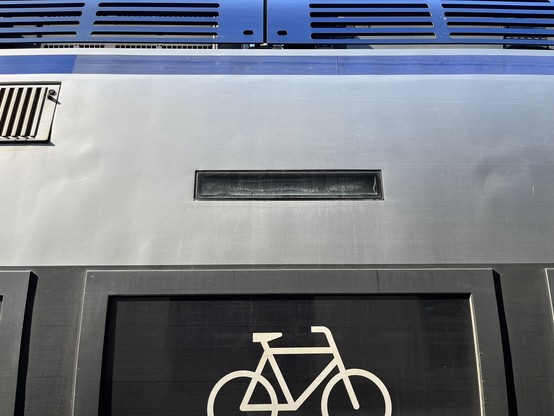 Broken sign on a train above a window with a bike logo