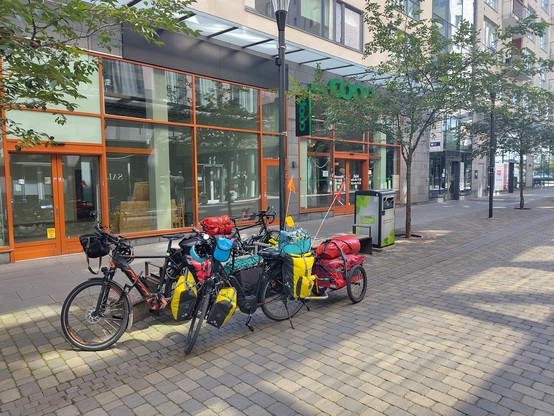 Vollbepackte Reisefahrräder mit Anhänger parken vor einem COOP Laden in Jönköping.