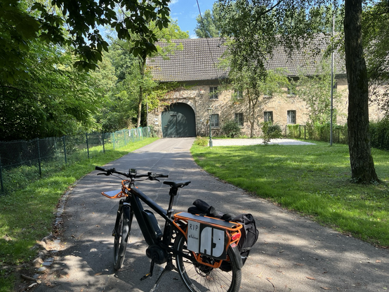 Das E-bike steht in der Zufahrt zum Wasserschloss Haus Graven