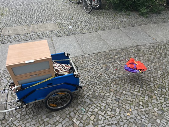 A bike trailer with drawers and a long metal frame in it