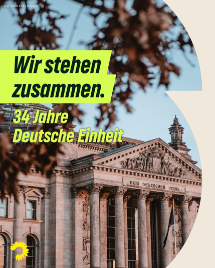 Auf dem Motiv ist in einem sandfarbenen, rundlichen Rahmen ein Bild des Reichstagsgebäudes mit zu erkennen. Auf dem alten Portal des Bauwerks erkennt man den Schriftzug „Dem Deutschen Volke“. Herbstlaub rahmt das Motiv im Vordergrund ein. Darüber steht auf einer gelbgrünen Farbfläche in dunkelgrüner Schrift: „Wir stehen zusammen.“ Und darunter „34 Jahre Deutsche Einheit“.  Am unteren linken Bildrand ist die Sonnenblume der Grünen Fraktion im Bundestag zu erkennen.